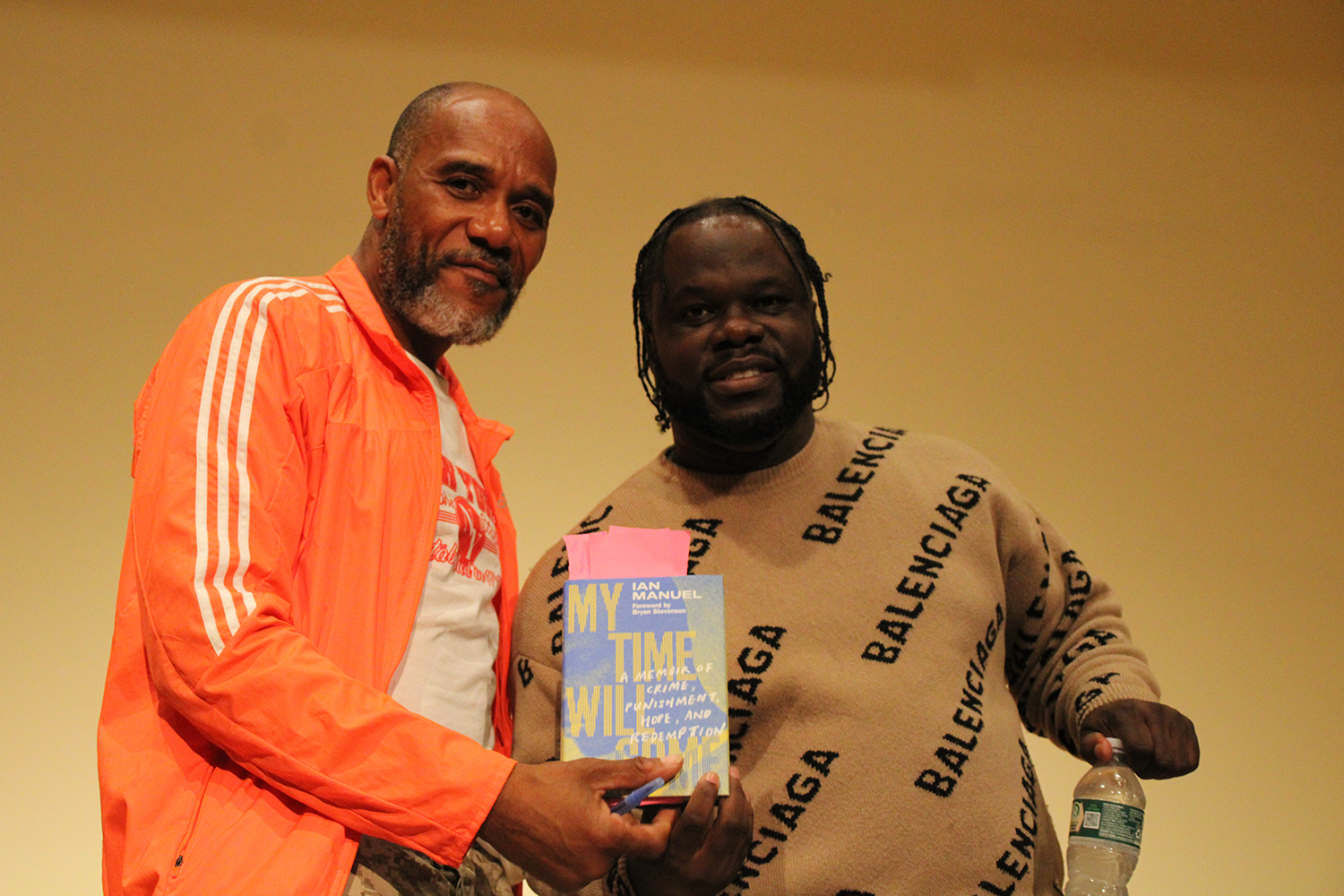 Two men hold a copy of a book with the title "My Time Will Come"