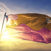 The red and gold flag of Bong County, Liberia, waves against the sky at sunrise