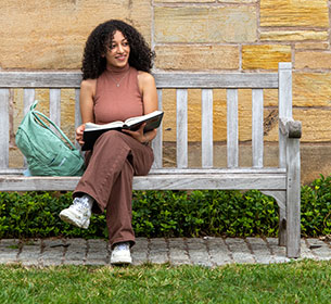 Student on bench of Yale's Cross Campus
