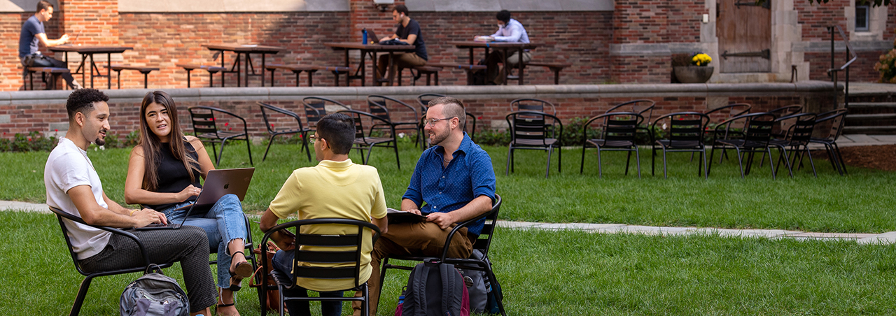 A group of students has a lively discussion in the YLS courtyard