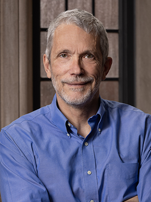 Ian Ayres with gray hair and a beard, wearing a blue button-down shirt