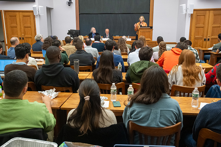 Students in a classroom with their backs to the camera listen to Dean Heather Gerken speak at the front of the room with Bob Bauer and Ben Ginsberg seated next to her.
