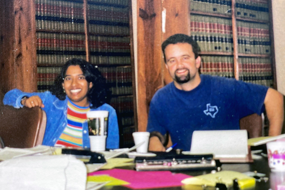 Doug Stevick ’96 and Lisa D’Souza reviewing sitting at a table with documents in front of shelves of law books.