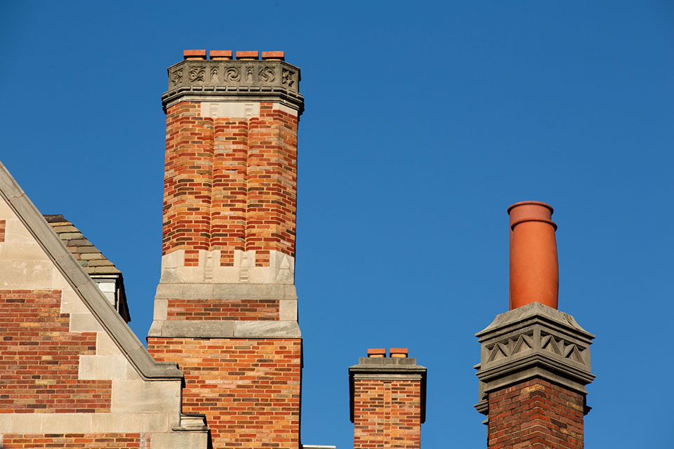 A row of brick chimneys atop Sterling Law Building against a blue sky