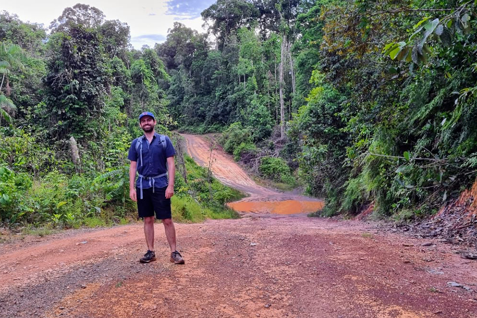 Jason Gardiner standing on a packed clay road through a wooded area