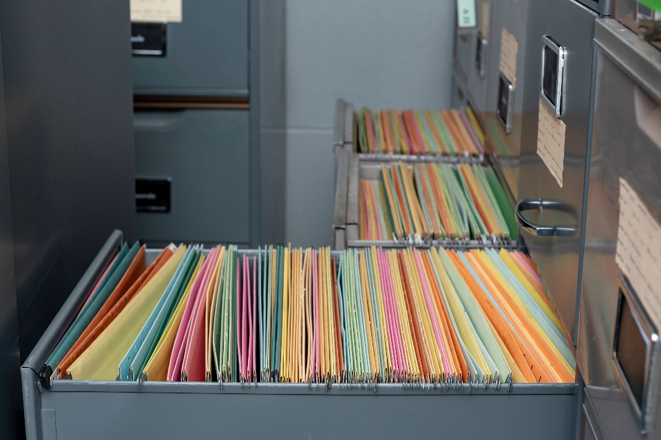 A filing cabinet with an open drawer, revealing colorful hanging file folders