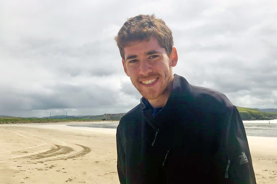 Tim Hirschel-Burns ’22 standing on a beach on a cloudy day