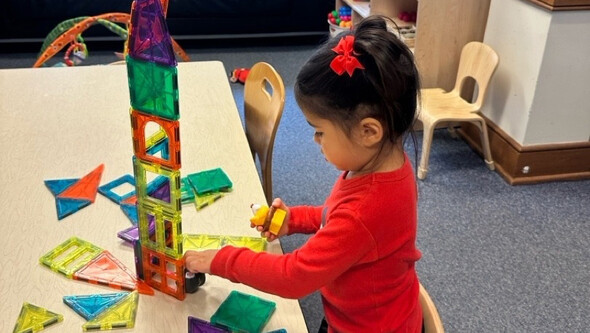 a girl in a red shirt building a tower with tiles