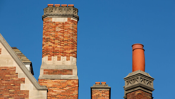 The roofline of Sterling Law Building with three brick chimneys of different sizes