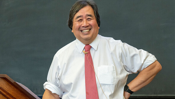 candid photo of harold koh smiling standing in front of blackboard
