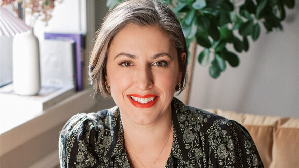 Jessica Valenti seated in a chair in a sunny room with greenery behind her