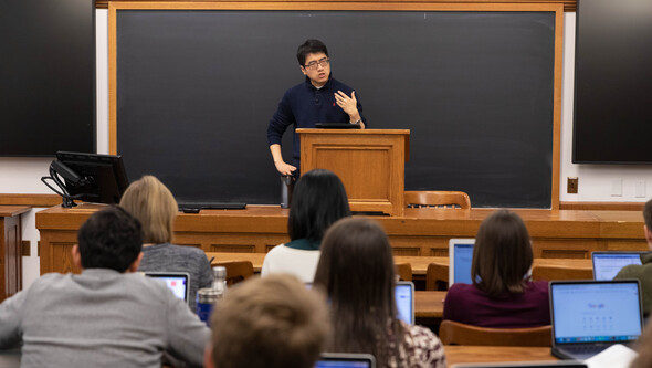 Professor Taisu Zhang teaching in a classroom in front of a blackboard and a group of seated students