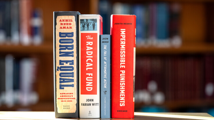 The spines of four faculty-written books