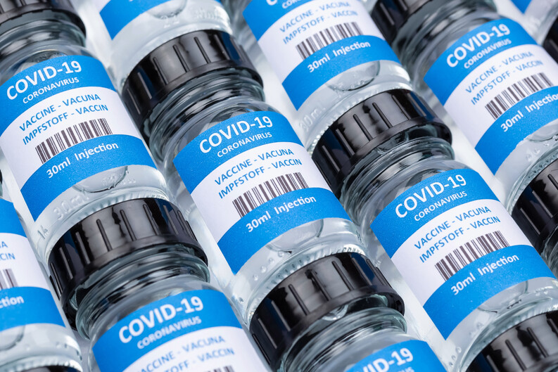 rows of glass vials with a label showing the words "COVID-19" and "VACCINE."