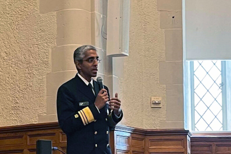 Surgeon General Vivek Murthy standing with microphone