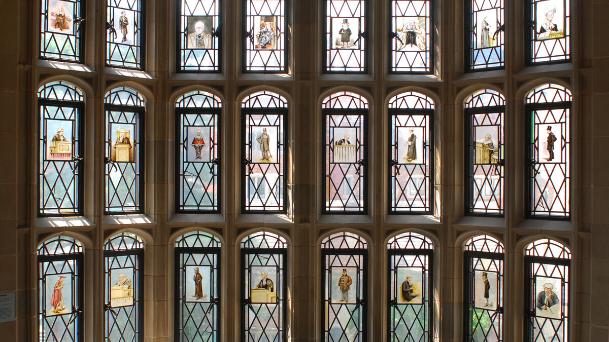 A close up of the stained glass windows in the main staircase showing caricatures of judges and lawyers.