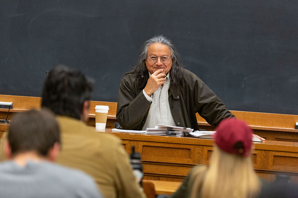 Professor Gerald Torres seated at table in front of a chalkboard