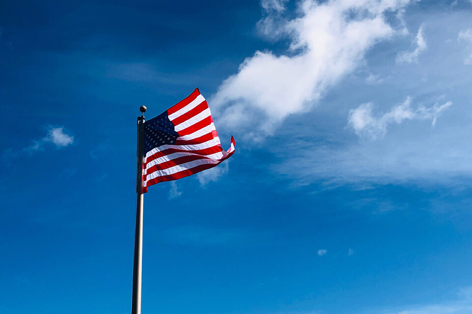 An American flag on a flag pole against a blue sky