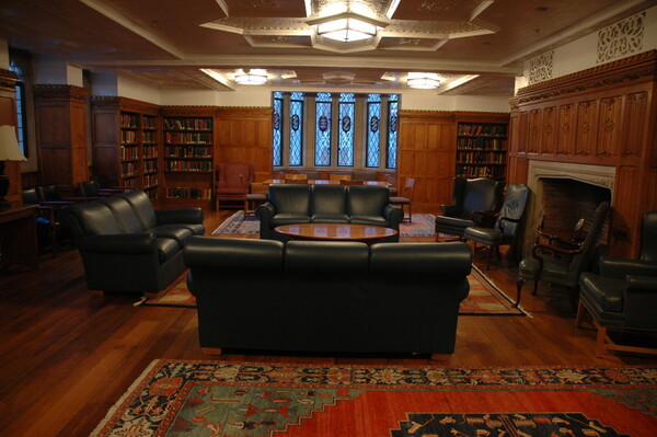 The Calabresi Faculty lounge often hosts events. A comfortable space with paneling, a fireplace, stained glass bay window, couches and chairs.