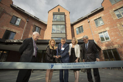 Robert Baker, Christina Baker hold scissors to cut a ribbon in front of Baker Hall with Heather Gerken and Peter Salovey looking on.