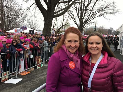 elizabeth esty and her daughter wearing purple in front of a barricade with other women behind