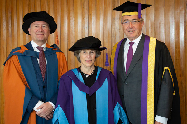 Judith Resnick wearing academic regalia standing between two men, also in academic regalia.