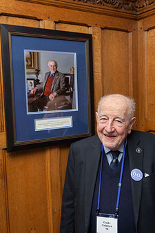 Guido Calabresi stands in front of his portrait hanging on a wall