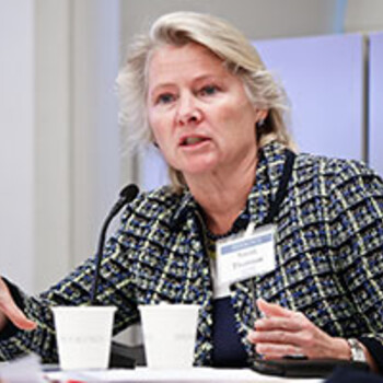 Susan Thornton seated at a table speaking into a microphone