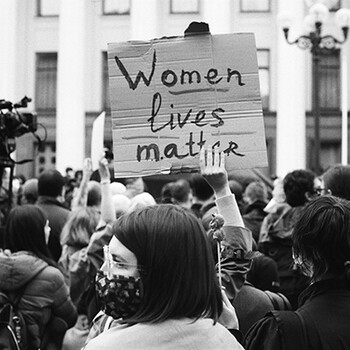 women in a rally holding a sign stating women lives matter