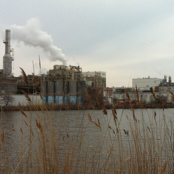 an industrial riverfront with smokestacks