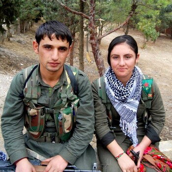 Two Kurdish soldiers, a man and a woman, sitting and looking at the camera.