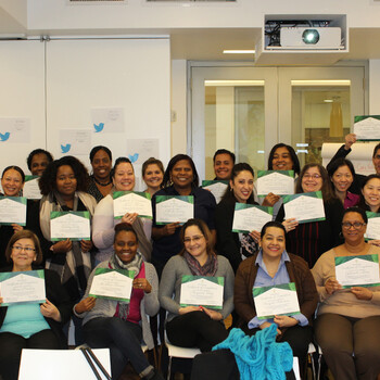 An All Our Kin childcare educator graduation (two rows of people hold their certificates)