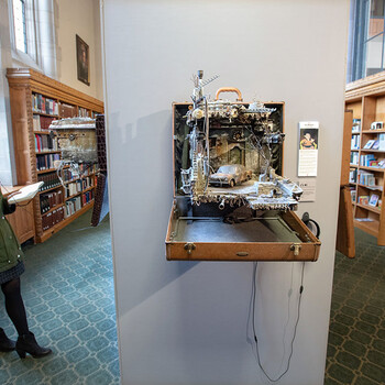 A female student listens to interview audio while looking at a piece of art in the Unpacked exhibit