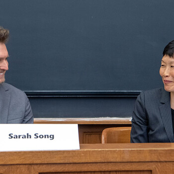 Paul Linden-Retek and Sarah Song sit in front of a classroom smiling at each other