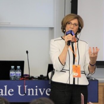 A woman speaking holding a microphone with a Yale University sign in the background