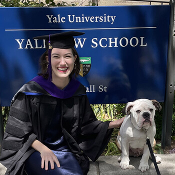 Allison Durkin wearing a graduation robe in front of the Yale Law School sign with the Yale bulldog
