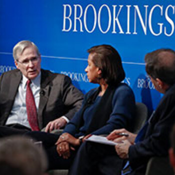 Former National Security Advisors Stephen Hadley and Susan Rice seated with Paul Gewirtz speaking to an audience in front of a blue background with a sign titled Brookings. 