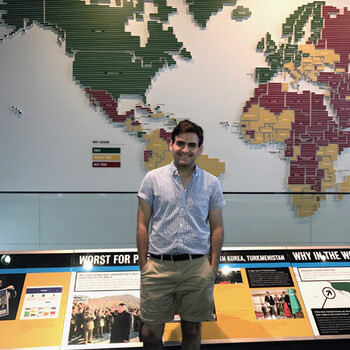 Michael Borger wearing shorts standing in front of a world map display
