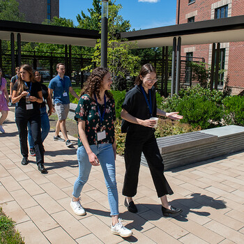 A group of students walking into the Baker Hall courtyard through a gate and across a walkway