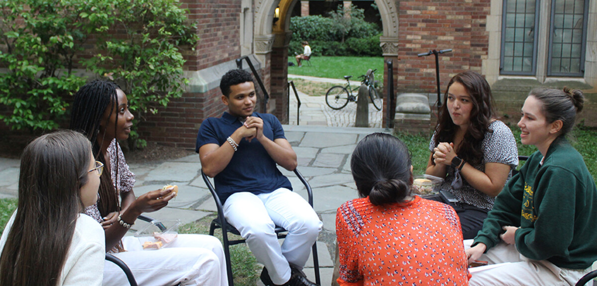 A group of students in conversation, seated in the courtyard