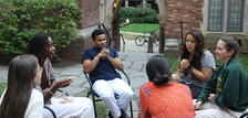 A group of students in conversation, seated in the courtyard