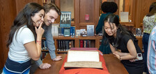 3 students examining a rare book in the YLS Law Library