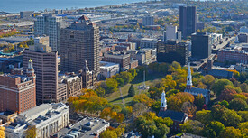 an aerial view of downtown New Haven with the Green, buildings, and Long Island Sound visible