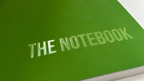 A book with a green cover and an embossed title "The Notebook"