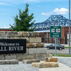 a sign says "Welcome to Fall River" in front of a large bridge