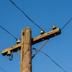 wooden telephone pole and wires against blue sky