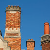The roofline of Sterling Law Building with three brick chimneys of different sizes