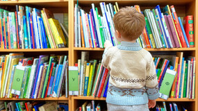 Child in a sweater browsing a shelf of books