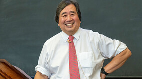 candid photo of harold koh smiling standing in front of blackboard
