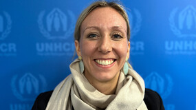 Lena Riemer before a blue backdrop printed with the United Nations High Commissioner for Refugees logo